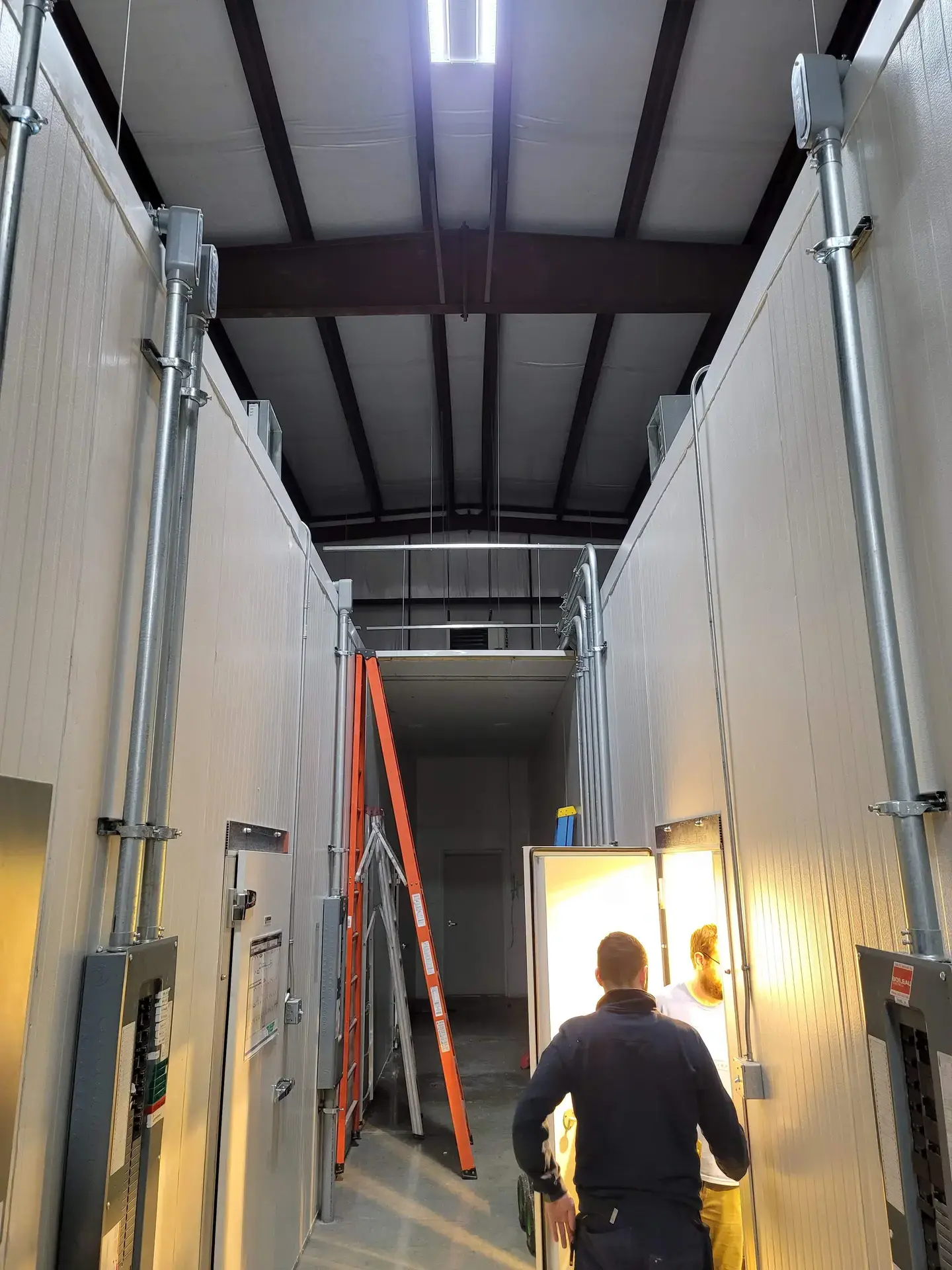 Technician running conduit for a walk-in freezer installation